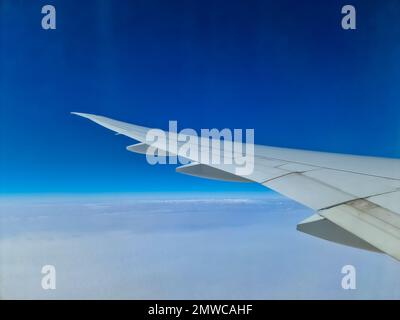 Blick von einem Flugzeug auf den Flügel und die Wolken darunter Stockfoto