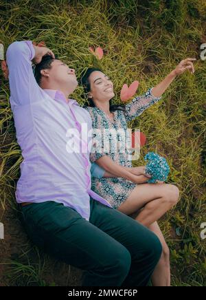 Hochzeitspaar liegt auf dem Gras, Paar liegt auf dem Gras, Liebes Stockfoto