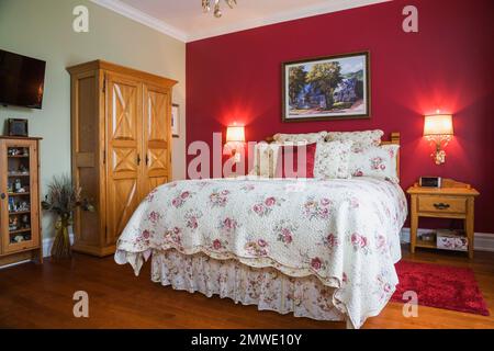 Queen-Size-Bett mit Eichenholz Nachttisch und Schrank im Hauptschlafzimmer im Erdgeschoss im zeitgenössischen Landhausstil. Stockfoto