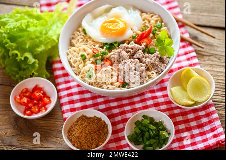 Nudelschüssel mit gekochtem Ei Hackfleisch Schweinefleisch Gemüse Frühlingszwiebeln Zitrone Limette Salat Sellerie und Chili auf dem Tisch Essen, Instantnudeln kochen leckeres Essen Stockfoto