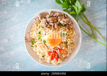 Nudelteller mit Eierhackfleisch aus Schweinefleisch, Frühlingszwiebelsellerie und Chili auf dem Tisch, Instant-Nudeln, leckeres Essen mit Schüssel Nudelsuppe Stockfoto