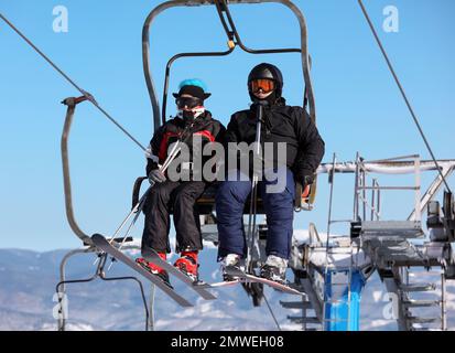 Leute, die den Sessellift im Mountain Ski Resort benutzen. Winterurlaub Stockfoto