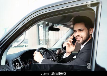 Attraktiver junger Mann, der während der Fahrt mit dem Smartphone spricht Stockfoto