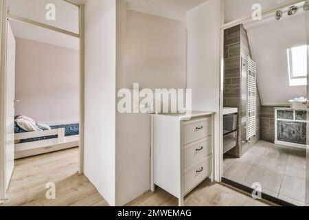 Ein Badezimmer mit Holzfußboden und weißen Schränken in der Ecke, neben einer begehbaren Duschkabine Stockfoto