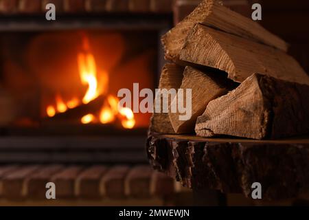 Ein Haufen Holz und ein verschwommener Kamin im Hintergrund, Platz für Text. Winterurlaub Stockfoto