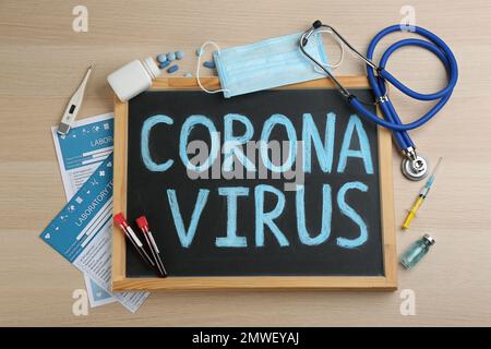 Tafel mit den Worten CORONA VIRUS, Stethoskop und Medikamente auf Holzhintergrund, flach liegend Stockfoto