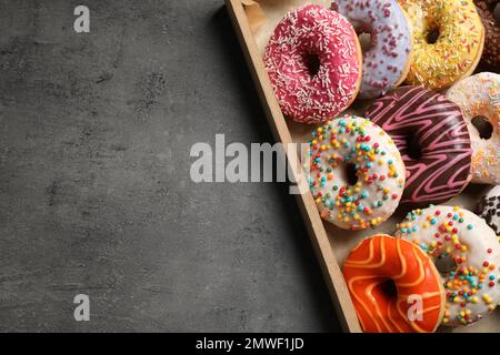 Draufsicht auf leckere Donuts mit Streuseln im Karton, Platz für Text Stockfoto