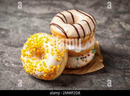 Süße, köstliche glasierte Donuts auf einem grauen Tisch Stockfoto