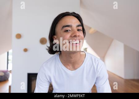 Ein glücklicher birassistischer Mann, der im Badezimmer in den Spiegel schaut Stockfoto