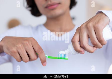 Ein glücklicher birassistischer Mann, der im Badezimmer Zähne putzt Stockfoto