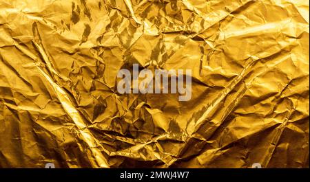 Leuchtend gelbe Textur aus zerknitterter und geknitterter Goldfolie oder Blatt als Hintergrund. Stockfoto