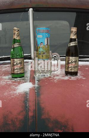 Bierflaschen und alte Bierdose mit einem Cartoon auf der Haube eines antiken Trucks. Stockfoto