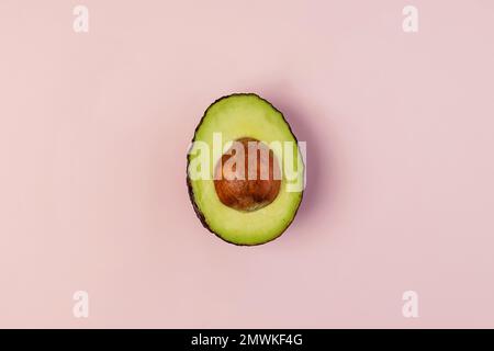 Avocado halb isoliert auf pinkfarbenem Hintergrund, Draufsicht Stockfoto