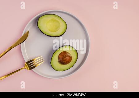 Reife Avocado, in Hälften auf der weißen Platte geschnitten, Draufsicht Stockfoto