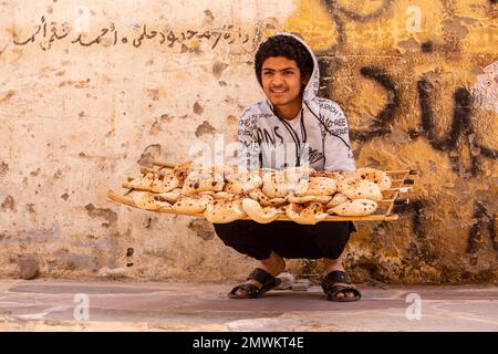 Ein Junge, der frisch gebackenes Brot in Assuan Old Souks, Assuan, Ägypten, verkauft Stockfoto