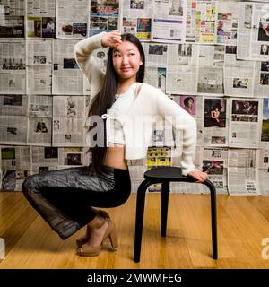 Ganzkörper-großes asiatisches Mädchen im Teenageralter vor dem Hintergrund von Zeitungen Stockfoto