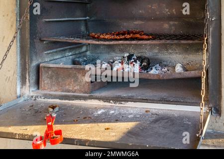 Schweinerippchen, Fleisch, Essen auf einem Metallgitter in einem Kamin über brennenden Kohlen und Holzkonzept Braai Heritage Day in Südafrika Stockfoto