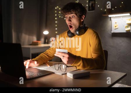 Schockierter Schüler mit Laptop hat kein Geld auf seiner Kreditkarte. Speicherplatz kopieren Stockfoto