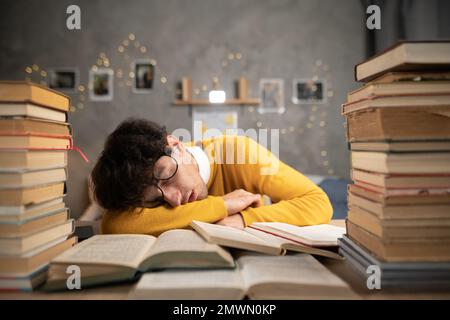 Ein müder Schüler mit Brille schläft auf den Büchern im Studentenwohnheim. Speicherplatz kopieren Stockfoto