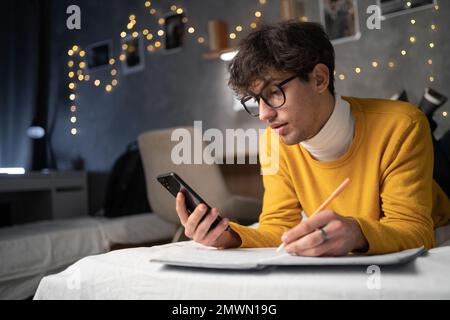Arabischer junger Student mit Smartphone, der am Handy studiert, Fernunterricht mit Apps für die Ausbildung, E-Learning auf dem Mobiltelefon im Universum Stockfoto