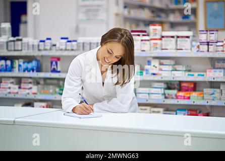 Nachverfolgung von Rezepten. Ein attraktiver junger Apotheker, der an der Rezepttheke arbeitet. Stockfoto