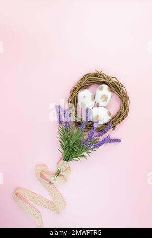 Weiße und goldene Eier in einem hölzernen Zweignest mit einem Blumenstrauß aus Lavendel und Schnur auf pinkfarbenem Hintergrund. Blick von oben. Ostern. Speicherplatz kopieren Stockfoto