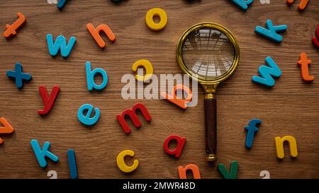 Buntes Alphabet mit einer Lupe. Lern- und Bildungskonzept. Schlüsselwörter werden gesucht. Sprachenlernen. Stockfoto