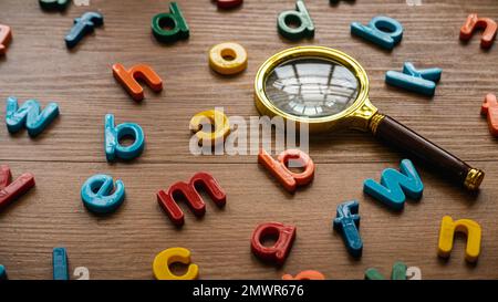 Buntes Alphabet mit einer Lupe. Lern- und Bildungskonzept. Schlüsselwörter werden gesucht. Sprachenlernen. Stockfoto