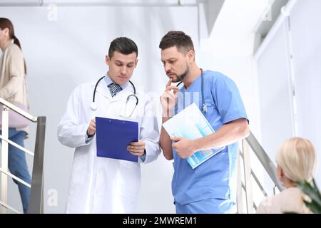 Arzte, die auf Treppen im Krankenhaus über die Patientendiagnose diskutieren Stockfoto