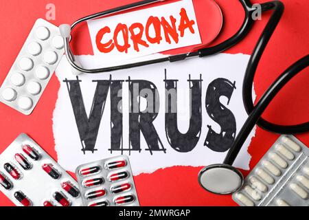 Flache Laienzusammensetzung mit Phrase CORONA-VIRUS und Medikamenten auf rotem Hintergrund Stockfoto