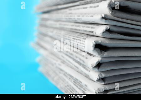 Zeitungsstapel auf hellblauem Hintergrund, Nahaufnahme. Journalistenarbeit Stockfoto