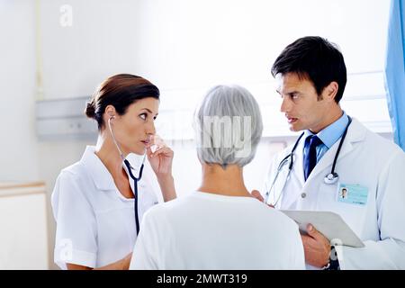Hörst du das? Zwei Ärzte untersuchen einen älteren Patienten. Stockfoto