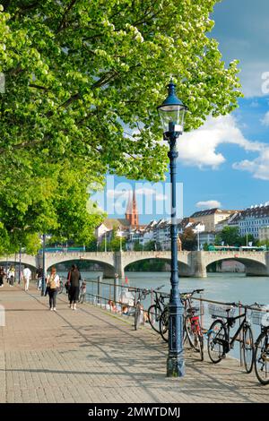 Blick vom Rheinufer entlang der Flusspromenade auf die Altstadt von Basel mit dem Basler Münster, der Mittleren Brücke und dem Rhein Fluss Stockfoto