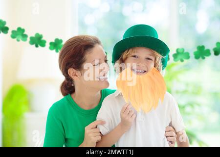 Mutter und Kind am St. Patricks Tag. St. Patrick-Tag-Feier. Kleiner Junge im Koboldkostüm. Grünes Shamrock-Konfetti. Stockfoto