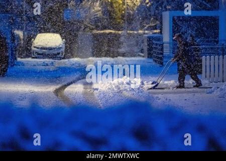 Straubing, Deutschland. 02. Februar 2023. Am frühen Morgen räumt ein Mann Schnee auf einer Straße. Kredit: Armin Weigel/dpa/Alamy Live News Stockfoto