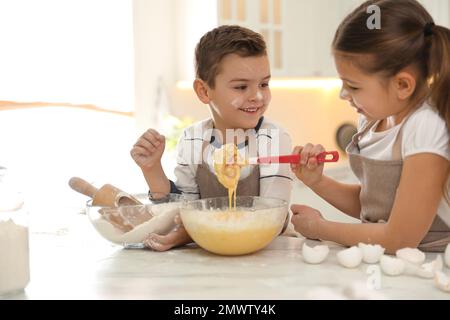 Süße kleine Kinder kochen Teig zusammen in der Küche Stockfoto