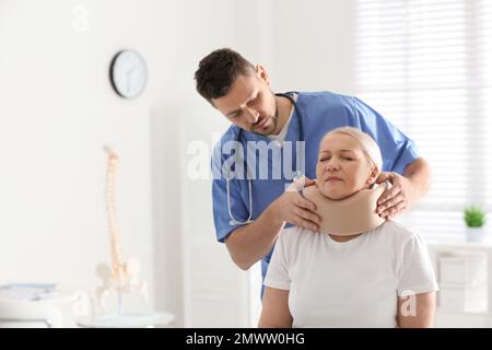 Orthopädin, der das Halsband am Hals des Patienten in der Klinik anlegt Stockfoto