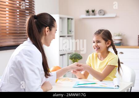 Ein kleines Mädchen, das eine professionelle Ernährungsberaterin im Büro besucht Stockfoto