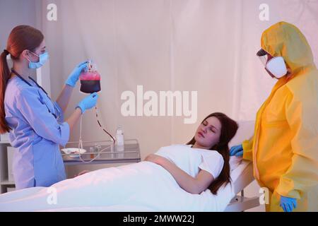 Professionelle Sanitäter untersuchen Patienten mit Virus in der Quarantänestation Stockfoto