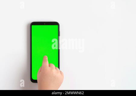 Kinderhand berührt Klick auf Mobiltelefon mit Chromakey-Bildschirm. „Little Baby Finger“ tippt in die Mitte des leeren grünen Telefondisplays. Schließen. Vetter Stockfoto