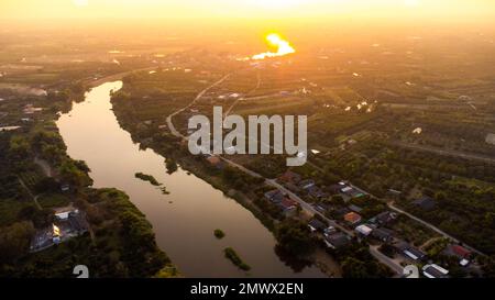 Luftaufnahme des Ping River über Reisfelder und ländliche Dörfer bei Sonnenuntergang. Blick auf die Dörfer von Chiang Mai und den Fluss Ping von einer Drohne aus. Stockfoto