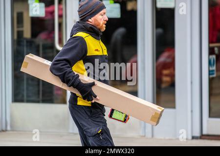 Zustellfahrer; DHL-Paketzustellung über ein mobiles Telefon in Southport, Merseyside UK, Großbritannien Stockfoto