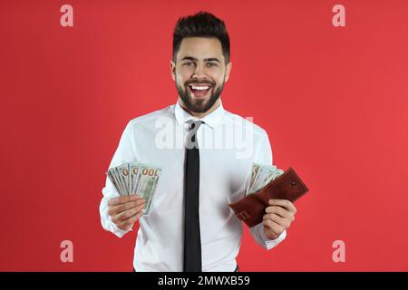 Emotionaler junger Mann mit Geld und Geldbörse auf purpurnem Hintergrund Stockfoto