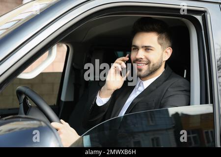 Attraktiver junger Mann, der während der Fahrt mit dem Smartphone spricht Stockfoto