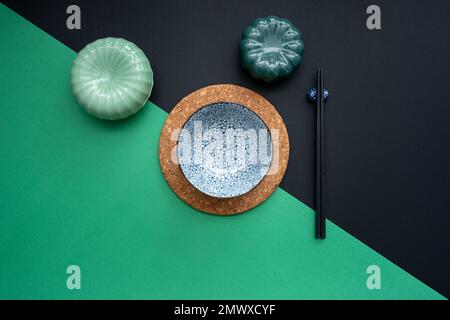 Japanischer oder chinesischer Tisch mit traditioneller Tischdecke und Essgeschirr mit grünem und schwarzem Hintergrund. Essen, Essen, Essen und Trinken Konzept. Stockfoto