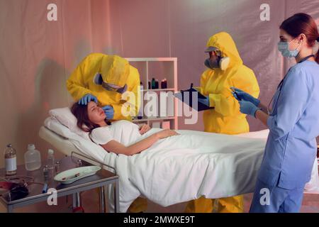 Professionelle Sanitäter untersuchen Patienten mit Virus in der Quarantänestation Stockfoto