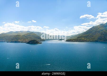 Panoramablick aus der Vogelperspektive auf den Comer See von Varenna in Richtung Bellagio mit klarem Himmel im Sommer und Booten auf dem Wasser. Stockfoto