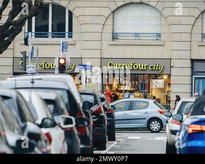 Straßburg, Frankreich - 31. Januar 2023: Perspektivblick durch geparkte Autos im Supermarkt Carrefour City im Stadtzentrum von Straßburg Stockfoto