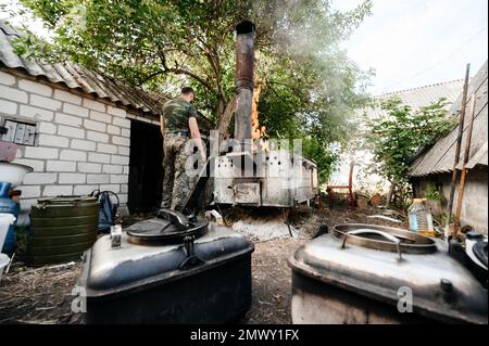 Ein Mann bereitet das Mittagessen in einer Militärküche zu, einem großen Holzspachtel zum Rühren von Essen. Stockfoto