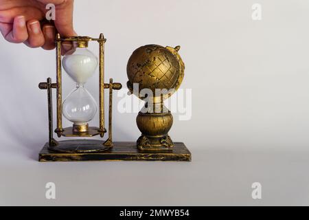 Sanduhr in der Hand. Erde und Sanduhr. Die Symbolik der Sanduhr. Stockfoto